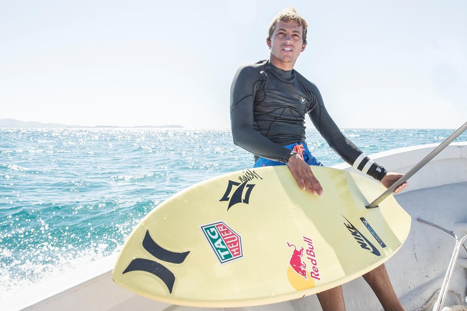 Kai Lenny holds up a hydrofoil surfboard.